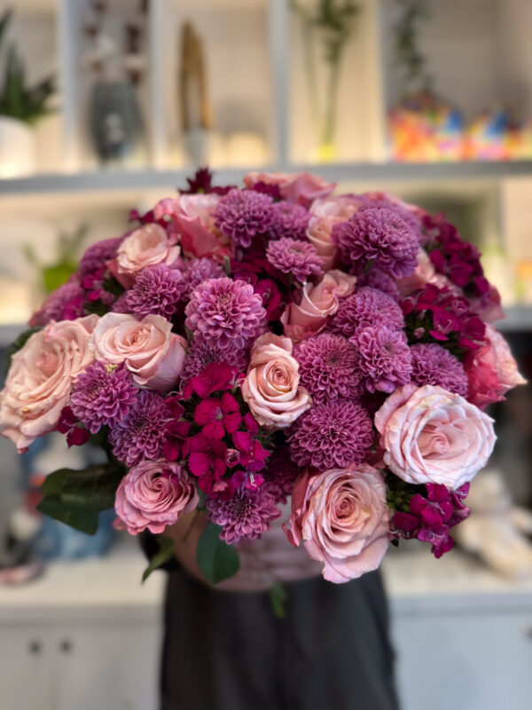 Στο επίκεντρο της σύνθεσης βρίσκονται τα ροζ ολλανδικά τριαντάφυλλα, γνωστά για τη φινέτσα και την πλούσια άνθισή τους.