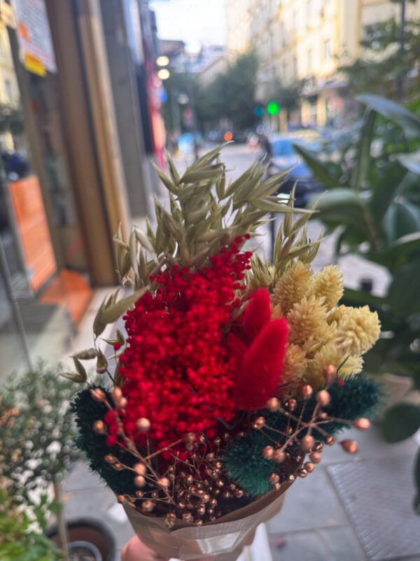 Η σύνθεση περιλαμβάνει αποξηραμένα στάχυα, amaranthus σε έντονο κόκκινο,bunny tails σε βαθύ κεραμιδί, χρυσαφένια άνθη και διακοσμητικά με μεταλλικές μπρονζέ πινελιές. Ο συνδυασμός των υφών δημιουργεί πλούσιο όγκο και γιορτινή διάθεση, χωρίς να απαιτείται καμία φροντίδα.