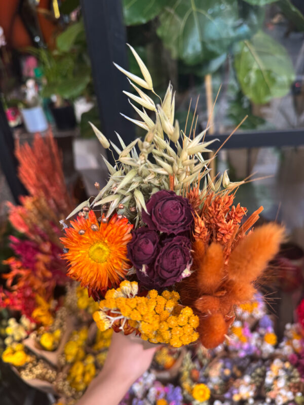 Μια ιδιαίτερη ανθοδέσμη με αποξηραμένα λουλούδια που συνδυάζει ζεστές φθινοπωρινές αποχρώσεις του πορτοκαλί, μπορντό και χρυσού. Δημιουργεί μια φυσική, cozy αίσθηση, ιδανική για διακόσμηση εσωτερικών χώρων ή ως μακροχρόνιο δώρο με διακριτική αισθητική.Περιλαμβάνει αποξηραμένα τριαντάφυλλα βαθύ κόκκινο, strawflowers σε πορτοκαλί–κεχριμπαρένιους τόνους, αποξηραμένα στάχυα και lago rus (bunny tails) σε καραμελέ και κεραμιδί αποχρώσεις.