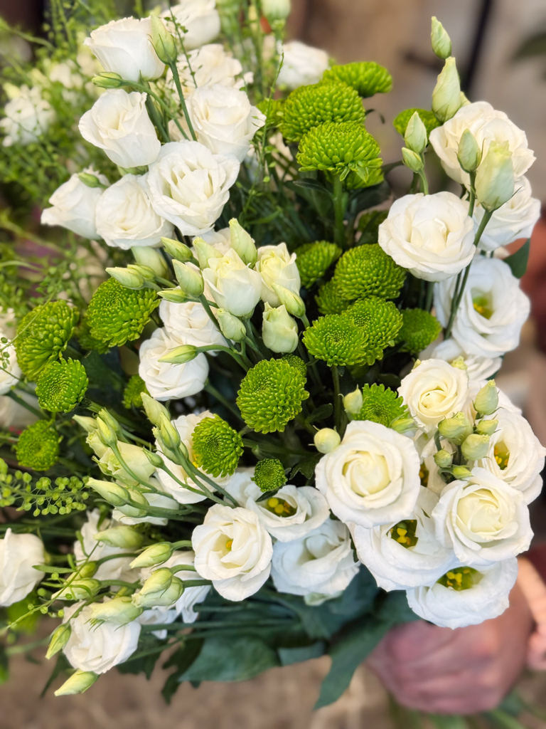 Κεντρικό ρόλο στη σύνθεση κατέχουν οι λυσίανθοι, λουλούδια που ξεχωρίζουν για τη λεπτότητα και την αέρινη υφή τους. Με τα απαλά λευκά πέταλα και τα πράσινα μπουμπούκια τους, αποπνέουν ρομαντισμό, αγνότητα και διακριτική φινέτσα.