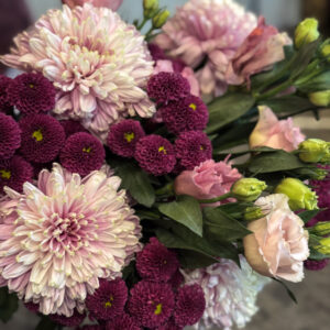 Οι λυσίανθοι στις απαλές ροζ αποχρώσεις τους λειτουργούν σαν «γέφυρα» ανάμεσα στα μωβ και τα λιλά χρυσάνθεμα, ενοποιώντας τη χρωματική παλέτα με φυσική χάρη. Είναι λουλούδια με διάρκεια, που διατηρούν τη φρεσκάδα τους για πολλές ημέρες, κάτι που κάνει την ανθοδέσμη ιδανική επιλογή τόσο για δώρο όσο και για διακόσμηση.