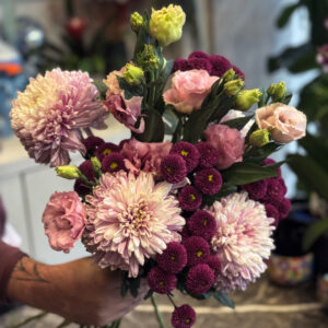 Στην ίδια σύνθεση, οι λυσιάνθοι προσθέτουν ένα πιο ρομαντικό και αέρινο στοιχείο. Πρόκειται για άνθη με λεπτά, μεταξένια πέταλα και πράσινα μπουμπούκια που σταδιακά ανοίγουν, συμβολίζοντας την αναγέννηση και τη φρεσκάδα.