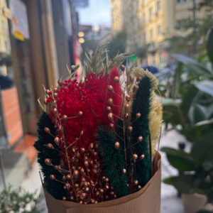 Μια εντυπωσιακή ανθοδέσμη με αποξηραμένα λουλούδια σε κόκκινες, χρυσές και πράσινες αποχρώσεις, εμπνευσμένη από τη ζεστασιά και τη λάμψη των γιορτών. Φτιαγμένη στο χέρι με προσεκτικά επιλεγμένα φυσικά υλικά, συνδυάζει τη διαχρονική κομψότητα με τον boho χαρακτήρα.